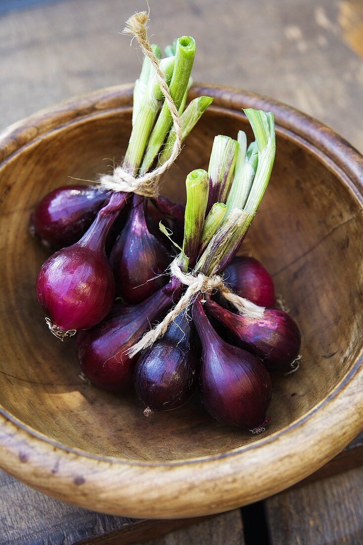 Bunches of red onions in a wooden bowl