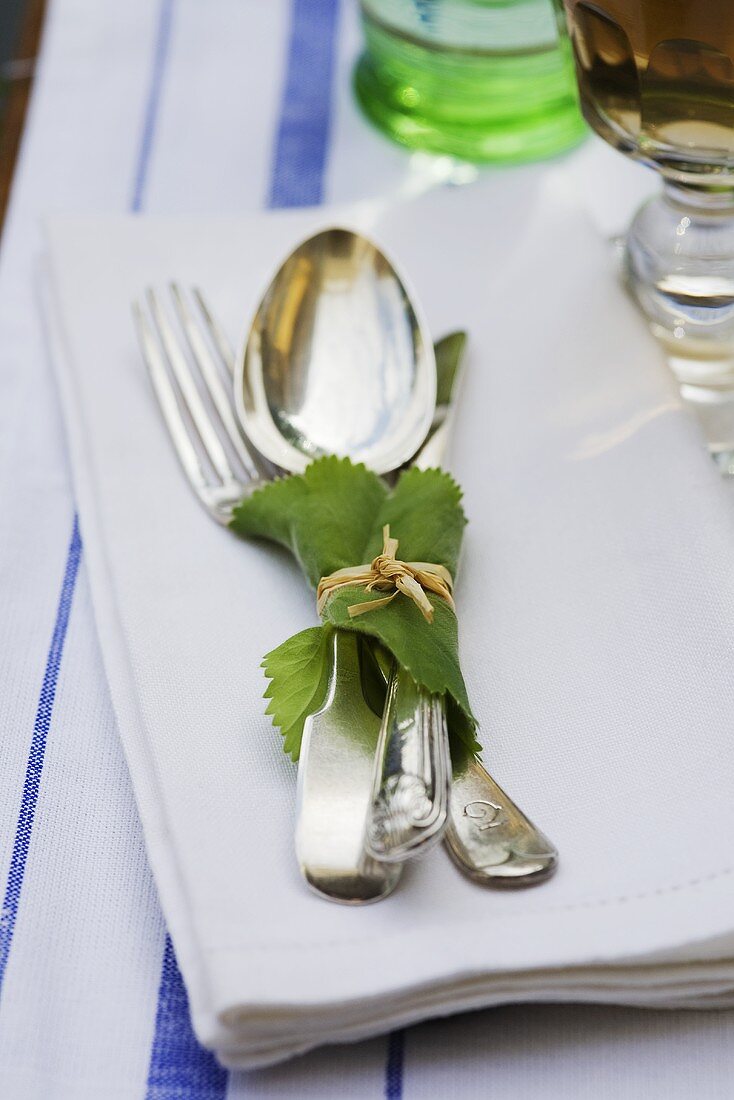 Cutlery wrapped in a vine leaf on a serviette