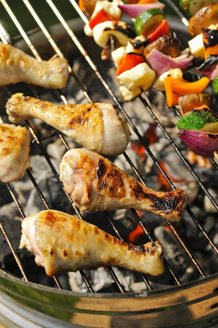 Chicken legs and vegetable kebabs on a barbeque