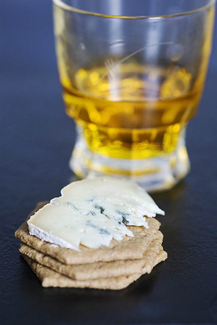 Blue cheese (type: Mrs Temple's Binham Blue, Norfolk, UK) on crackers with a glass of whiskey