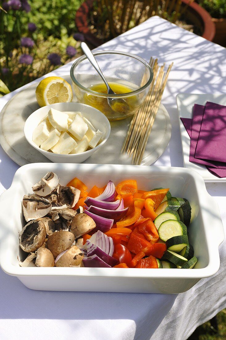 Zutaten für marinierte Gemüsespiesse auf Tisch im Freien