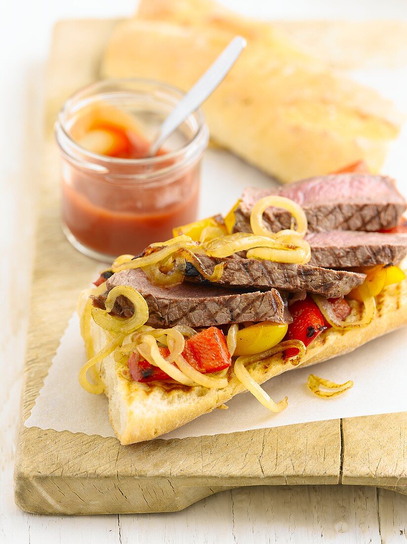 A steak sandwich with onions and peppers