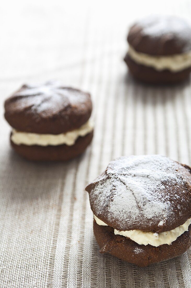 Three chocolate whoopie pies with icing sugar
