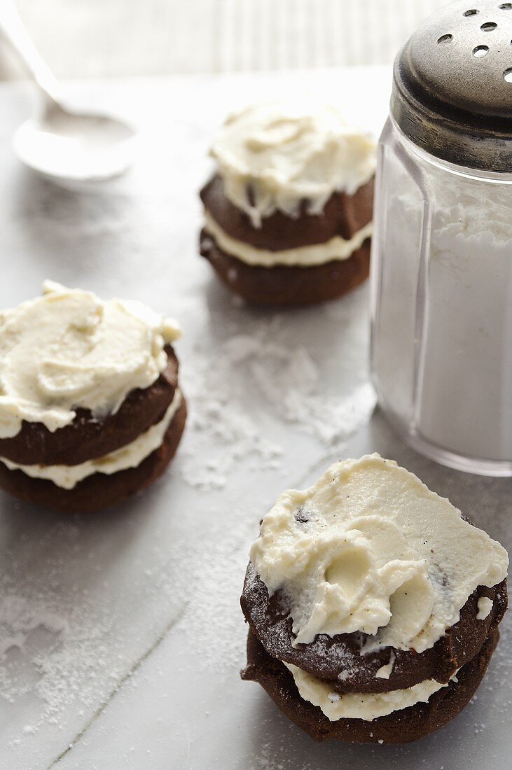 Drei Schokoladen-Whoopie Pies mit Creme und Puderzucker