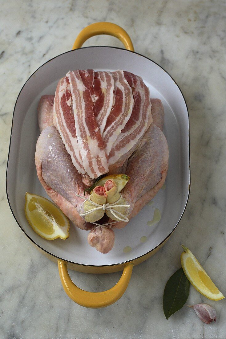 Bratfertiges Huhn mit Speckscheiben belegt