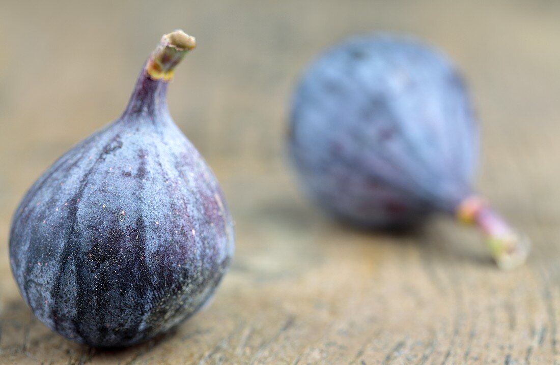 Two figs on a wooden surface