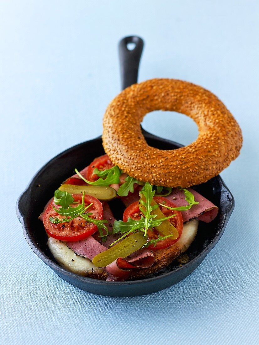 Toasting a bagel with pastrami in a pan
