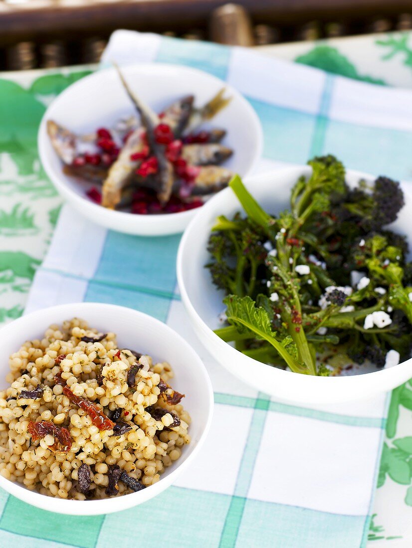 Pasta pearls with olives and dried tomatoes, broccoli, fried sprats with cranberries