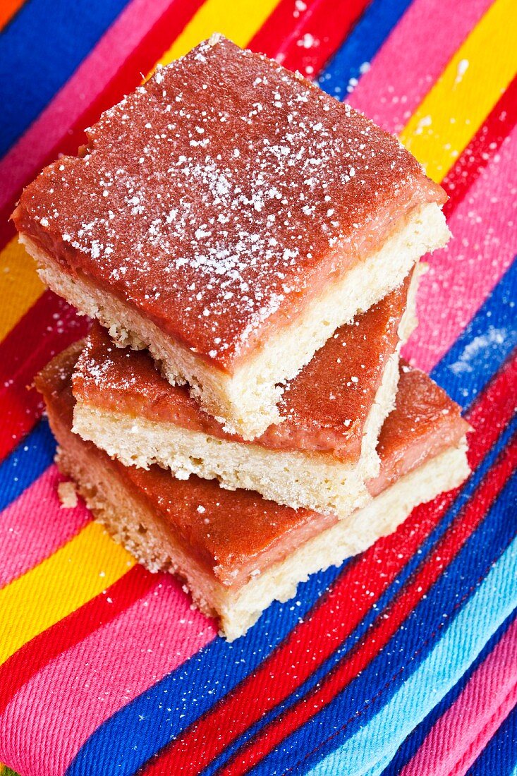 Rhubarb bars, stacked, on a striped cloth