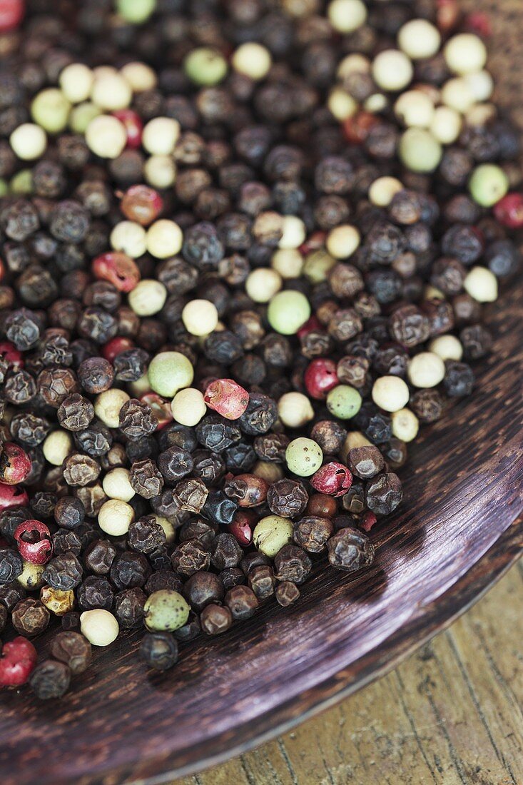 Various peppercorns in a wooden bowl (detail)