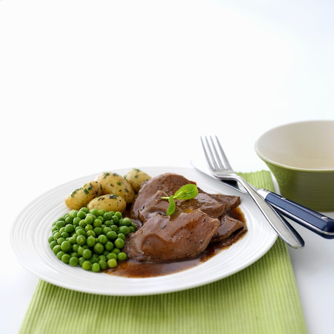 Sliced roast lamb with peas and potatoes