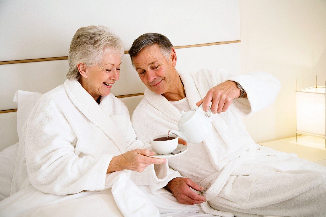 Älteres Paar trinkt Frühstückskaffee im Bett