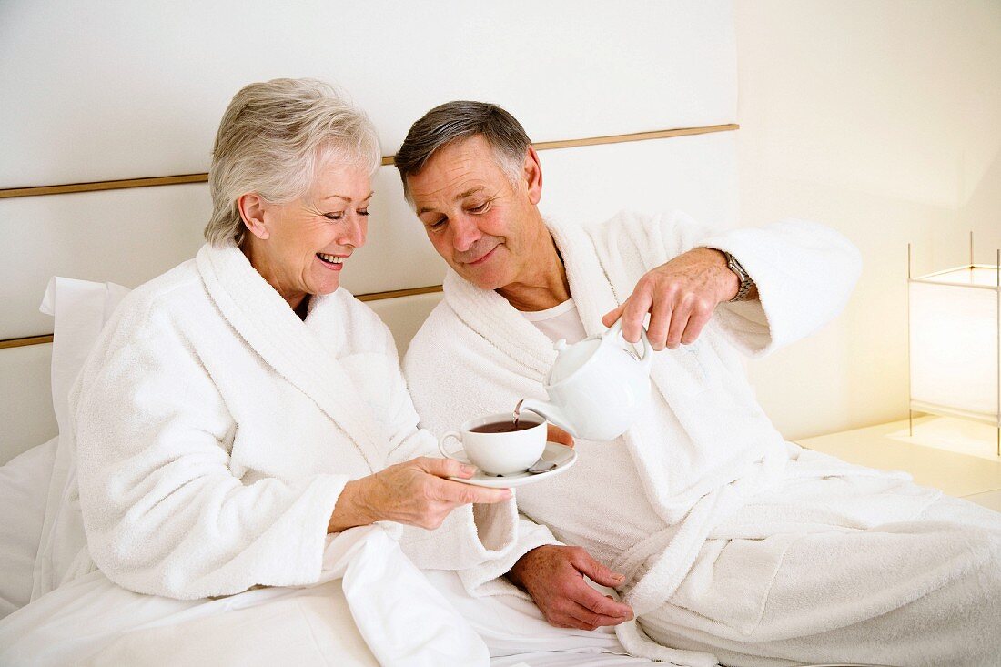 Older couple drinking a morning cup of tea in bed