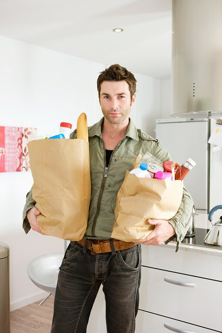 Mann mit Einkaufstüten in der Küche