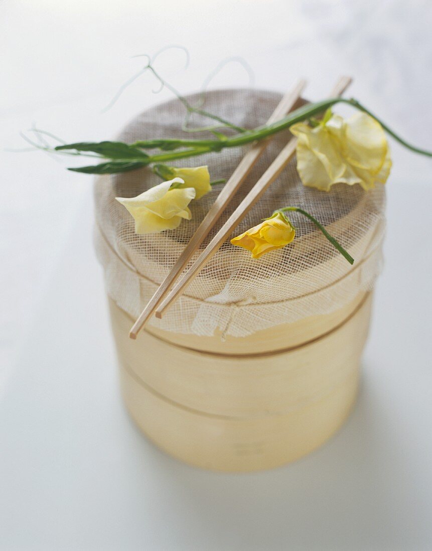 Bamboo basket with cheesecloth, chopsticks and flowers