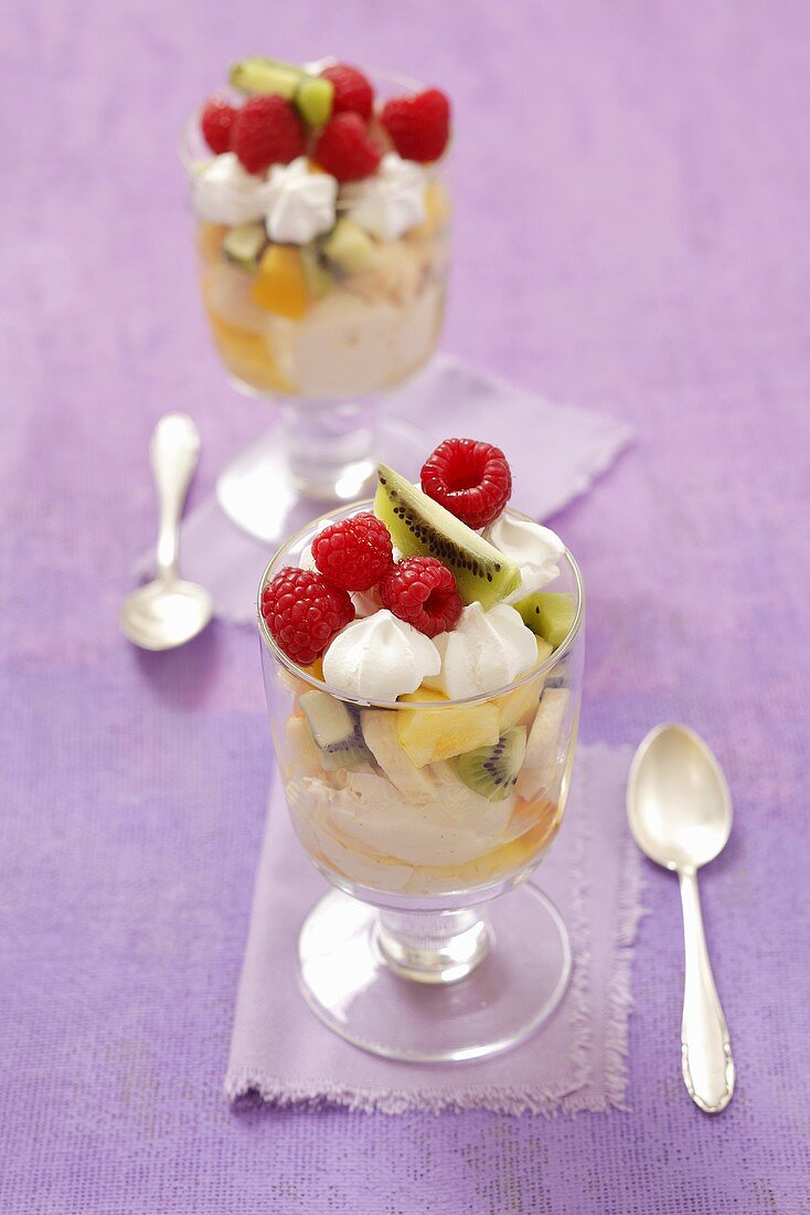 Two ice cream sundaes with vanilla ice cream, fresh fruit and meringue