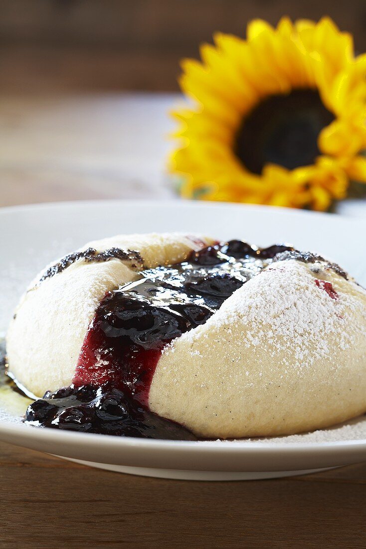 A Dampfnudel (steamed, sweet yeast dumpling) with poppy seed butter and fruit sauce