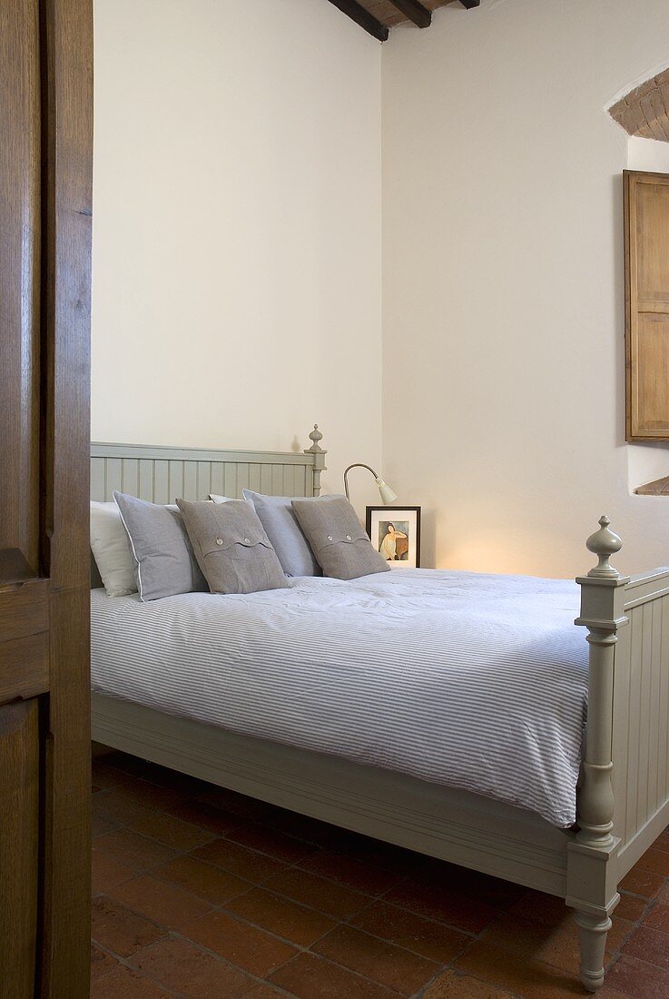 Double bed with a bright green wooden bed stead in a bedroom (country style)