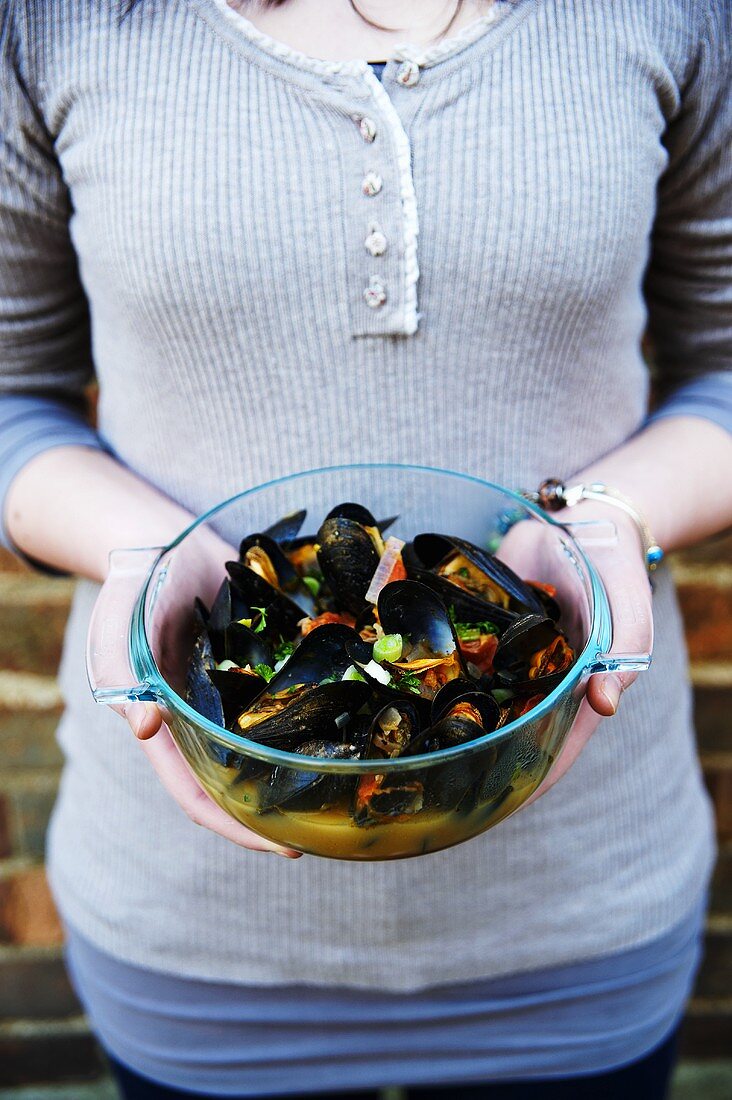 A woman holding a bowl of mussels