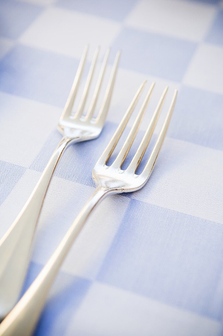 Two forks on a checked tablecloth