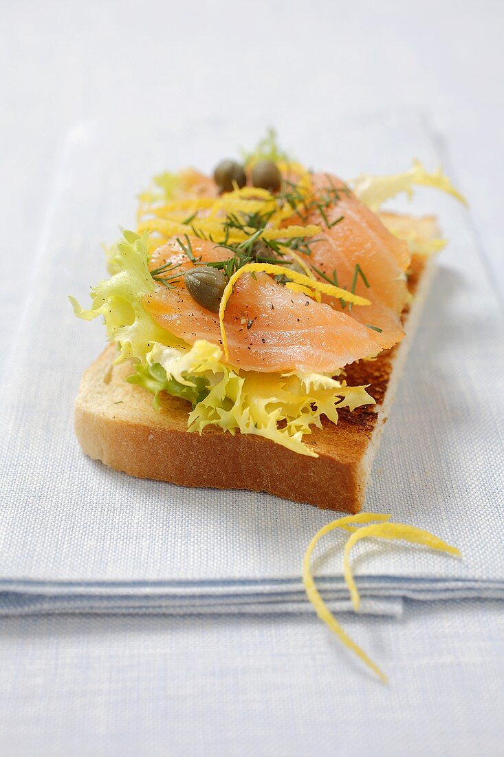 Toasthälfte mit Salat, Lachs und Kapern