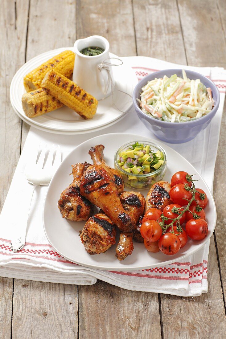Grilled chicken legs with cherry tomatoes, coleslaw and corn cobs