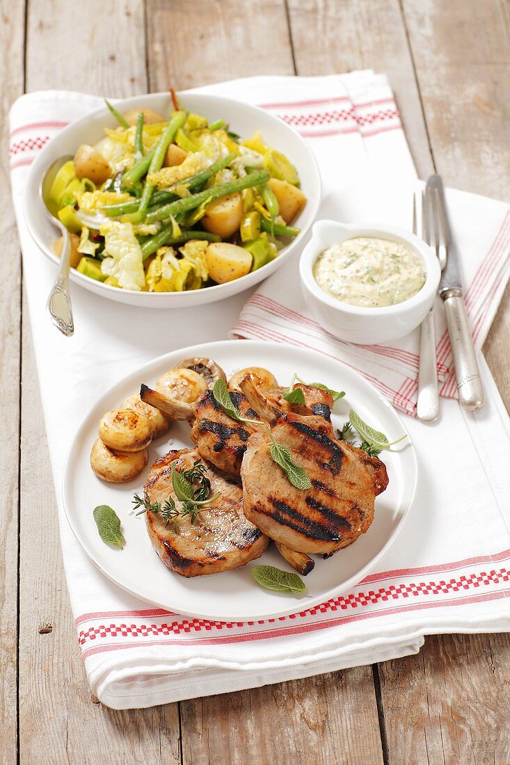 Grilled pork shops with a mustard dip and a potato and bean salad