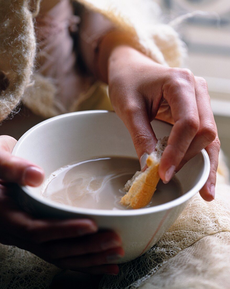 Brot in der Hand und tunkend in Kaffeeschale