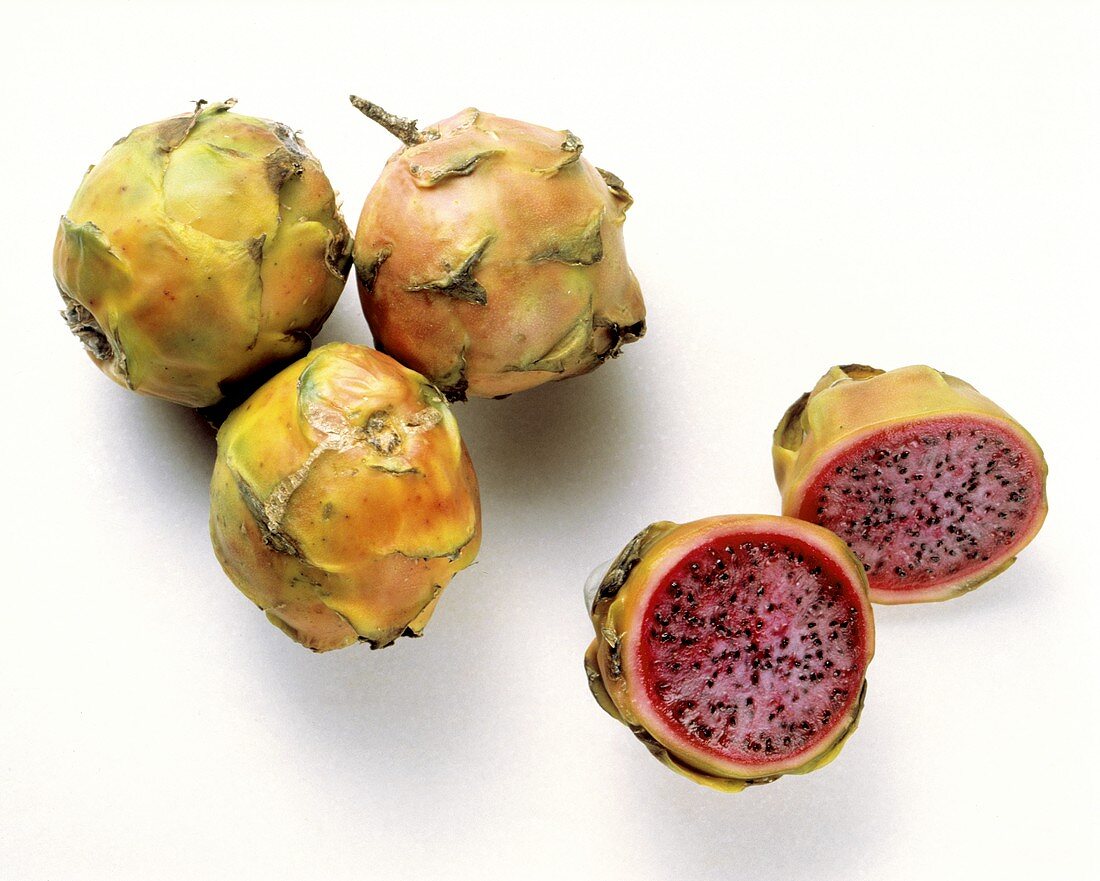 Drei ganze & eine halbierte Pitahaya mit rotem Fruchtfleisch