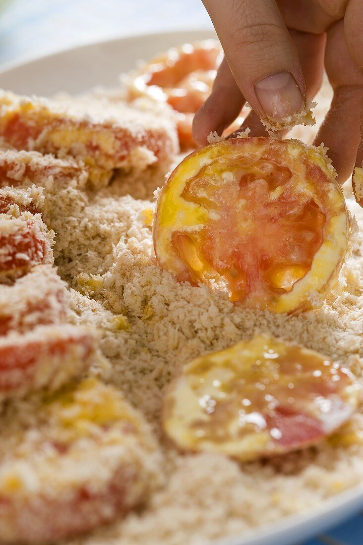 Tomato slices being dusted in breadcrumbs