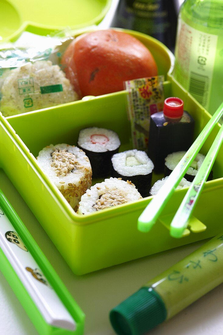 A box of sushi with wasabi and soy sauce