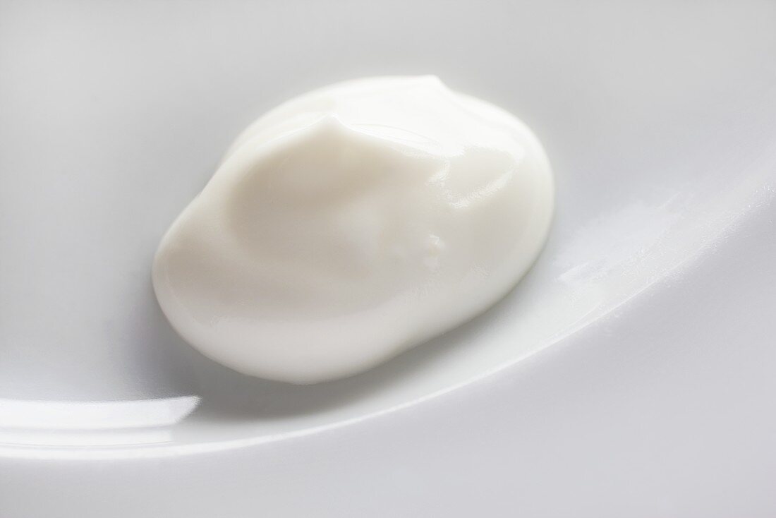 Ein Klecks Joghurt auf weißem Teller
