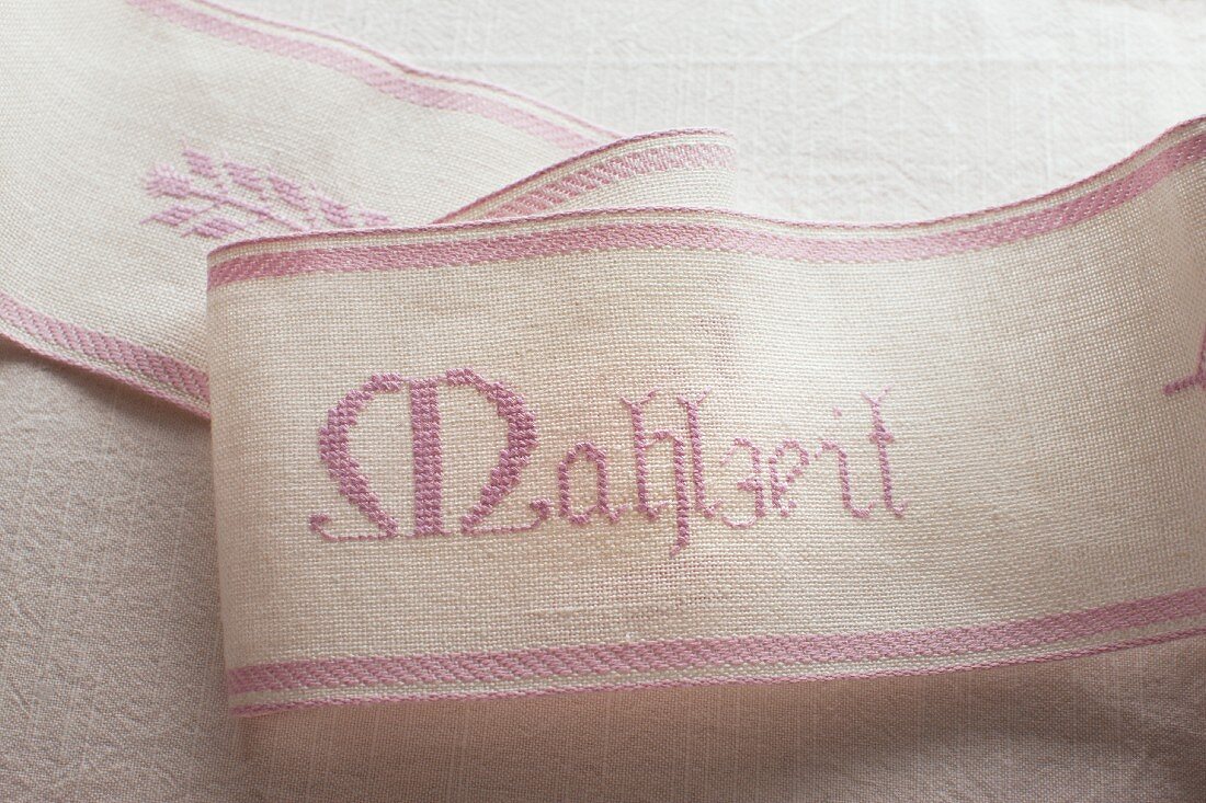 A ribbon embroidered with the word 'Mahlzeit'