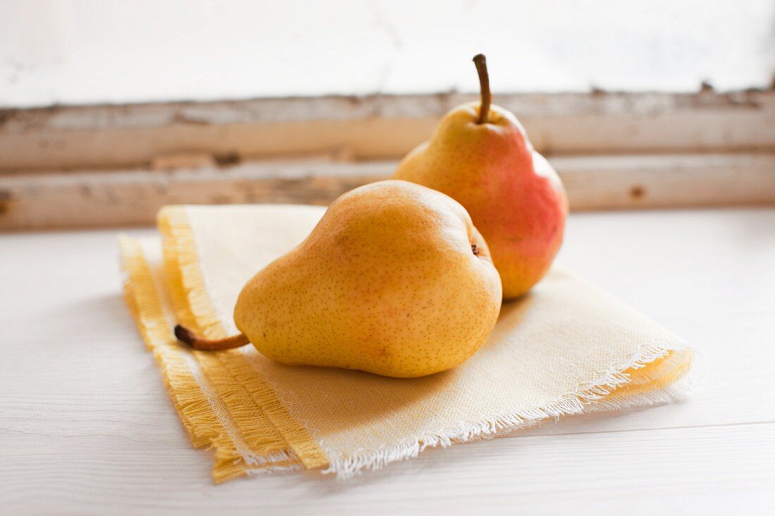Two pears on a cloth by a window