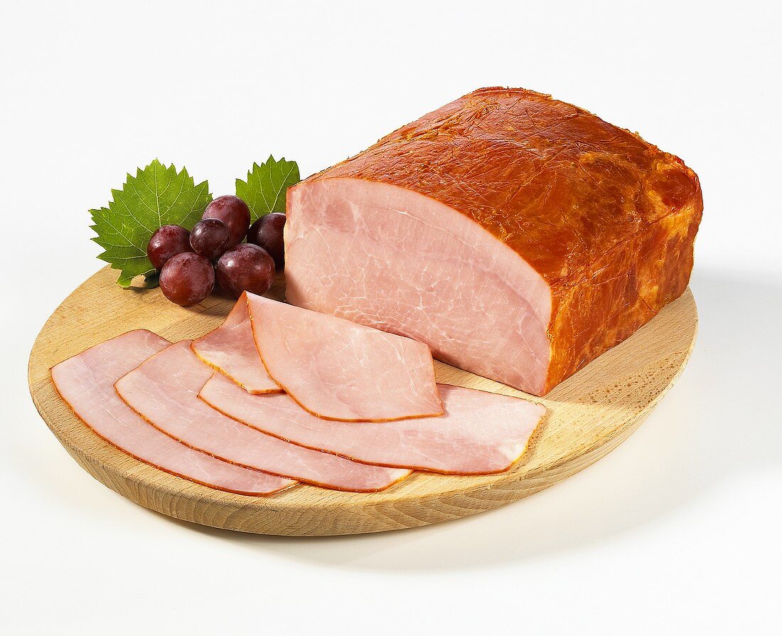 Sliced burgundy ham on a wooden plate