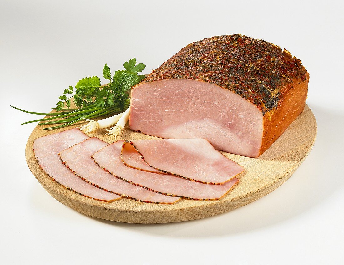 Sliced herb ham on a wooden plate