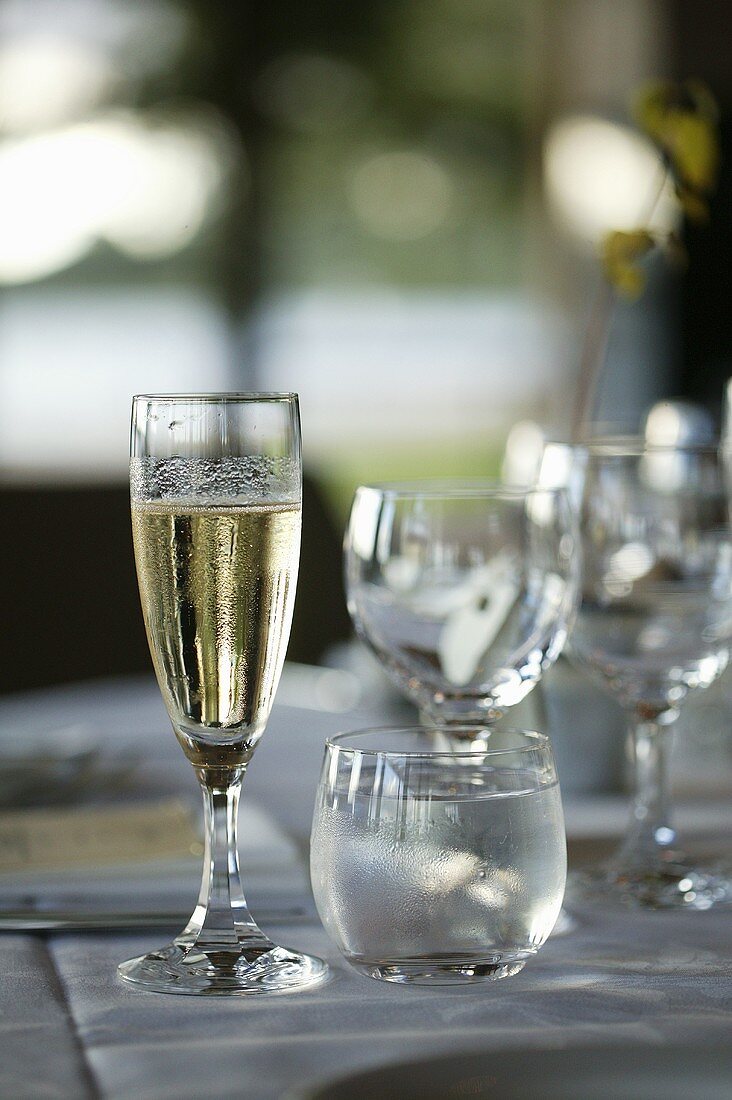 A glass of champagne and a glass of water on a laid table