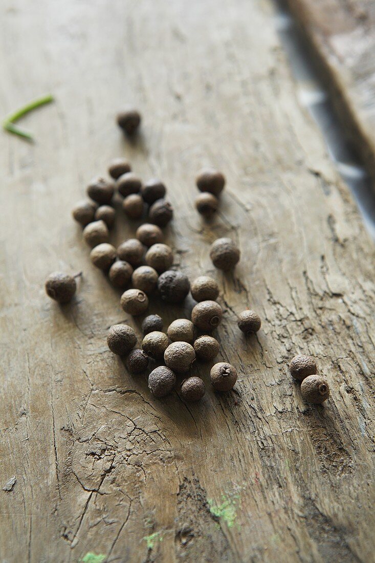 Black peppercorns on a wooden surface