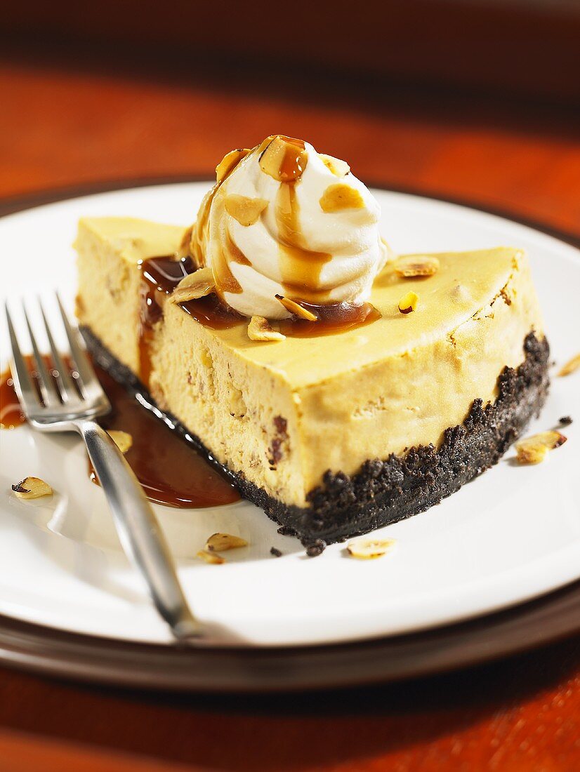 A slice of coffee cheesecake with cream and caramel sauce