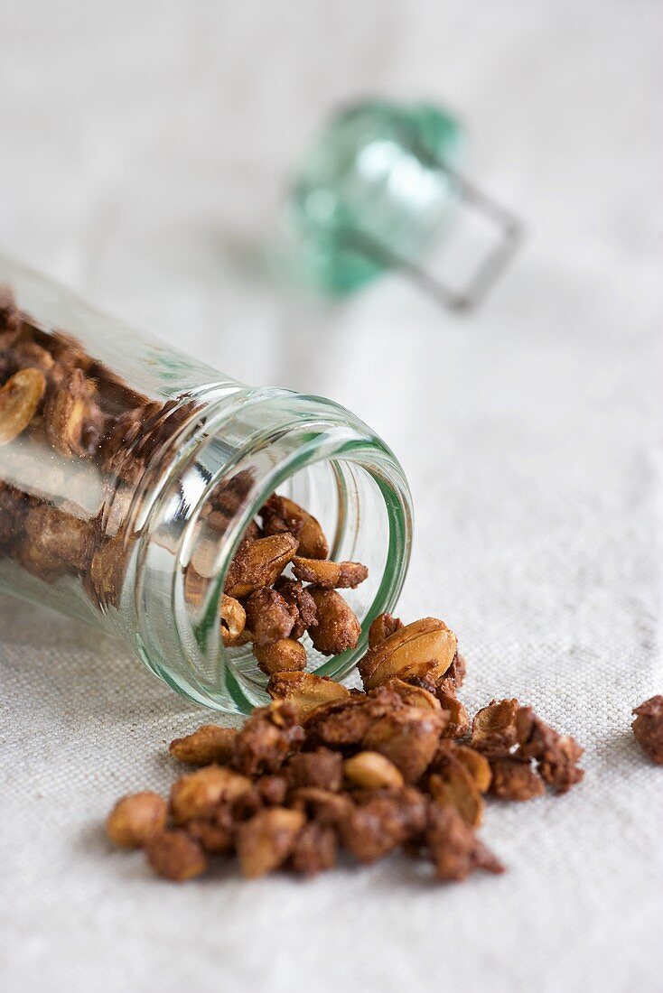 Roasted peanuts spilling out of a jar