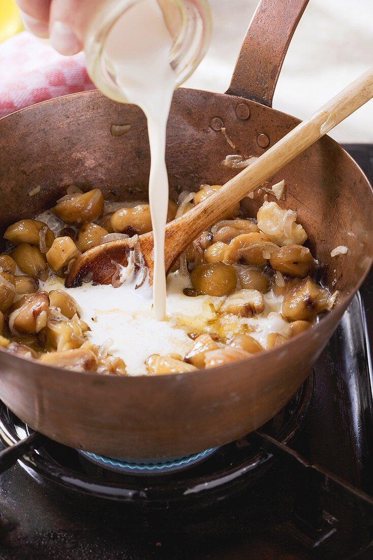 Cream being added to onions, garlic and chestnuts