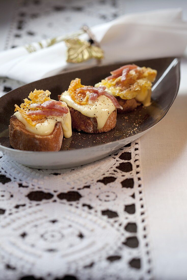 Crostini topped with bacon and Vacherin cheese
