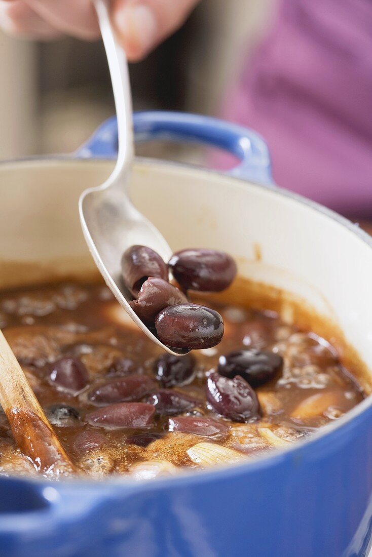 Schwarze Oliven zu der Lammsauce geben