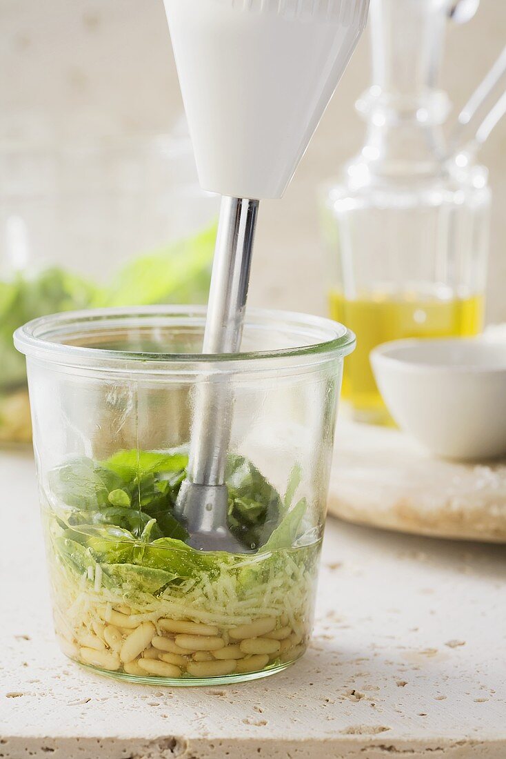 Pesto ingredients being mixed with a hand blender