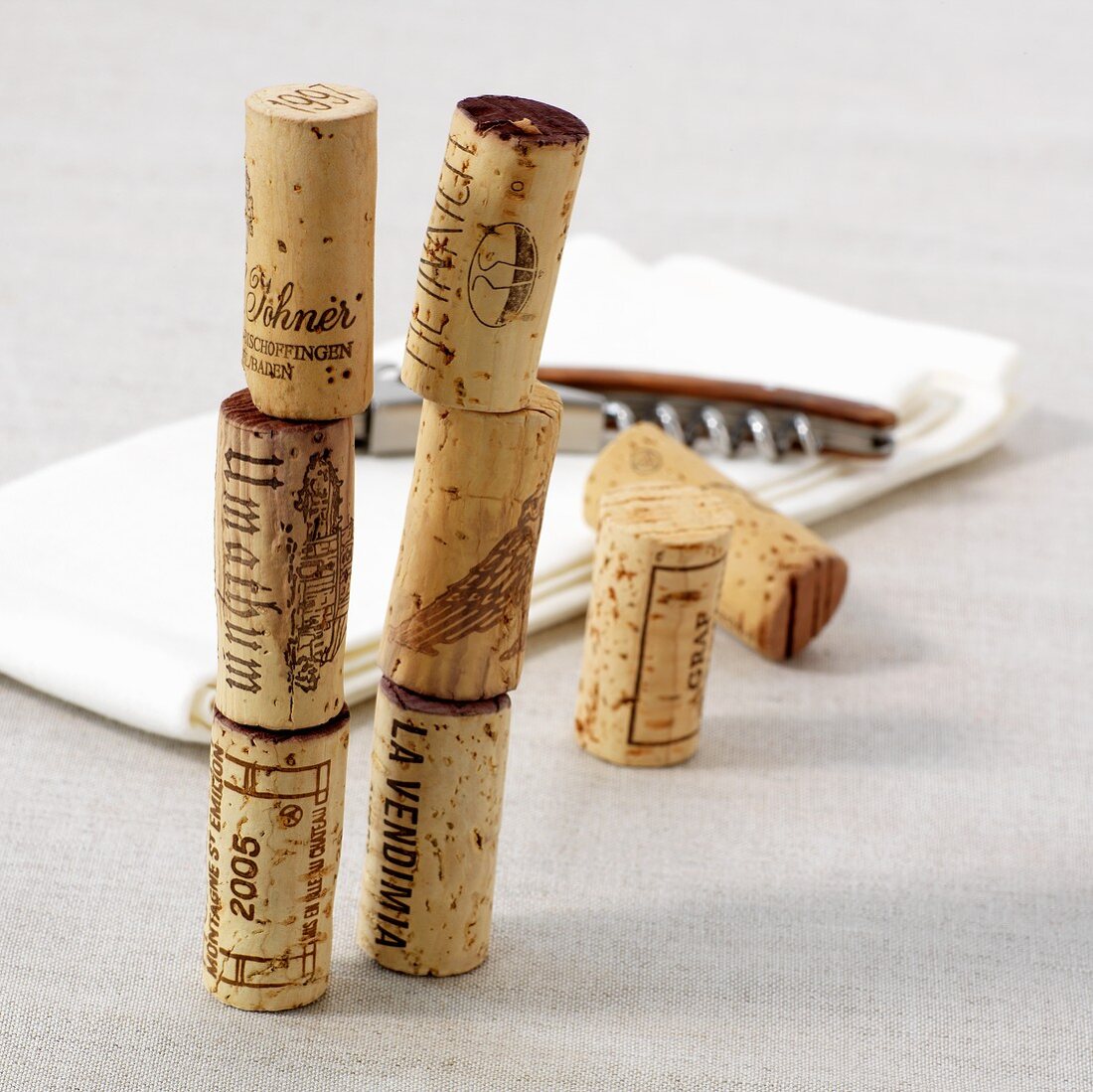 A stack of wine corks, a corkscrew and a cloth