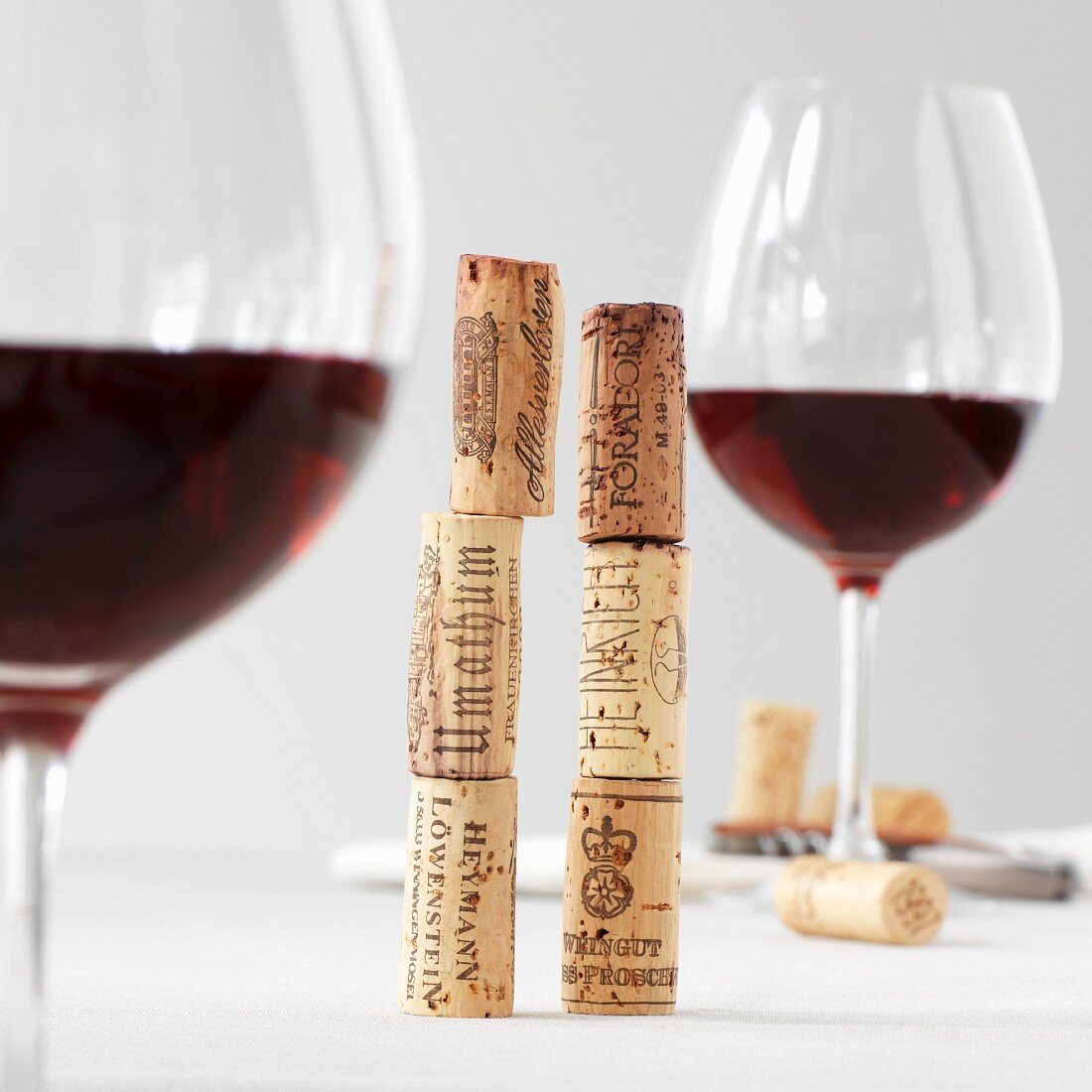 Two stack of wine corks between two glasses of red wine