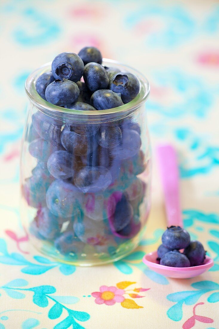 Fresh blueberries in a glass and on a spoon