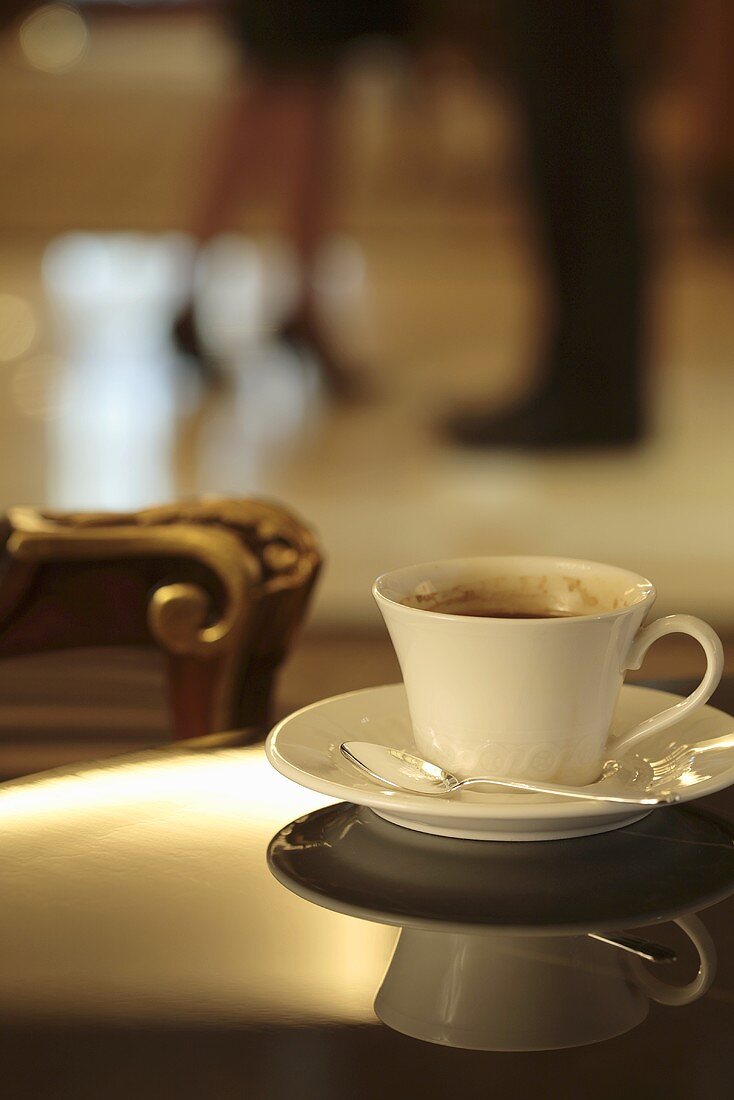 Eine Kaffeetasse reflektiert auf einem blitzblanken Tisch
