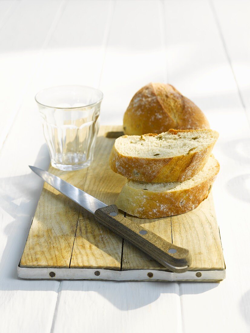 White bread slices, knife and empty glass on a cutting board