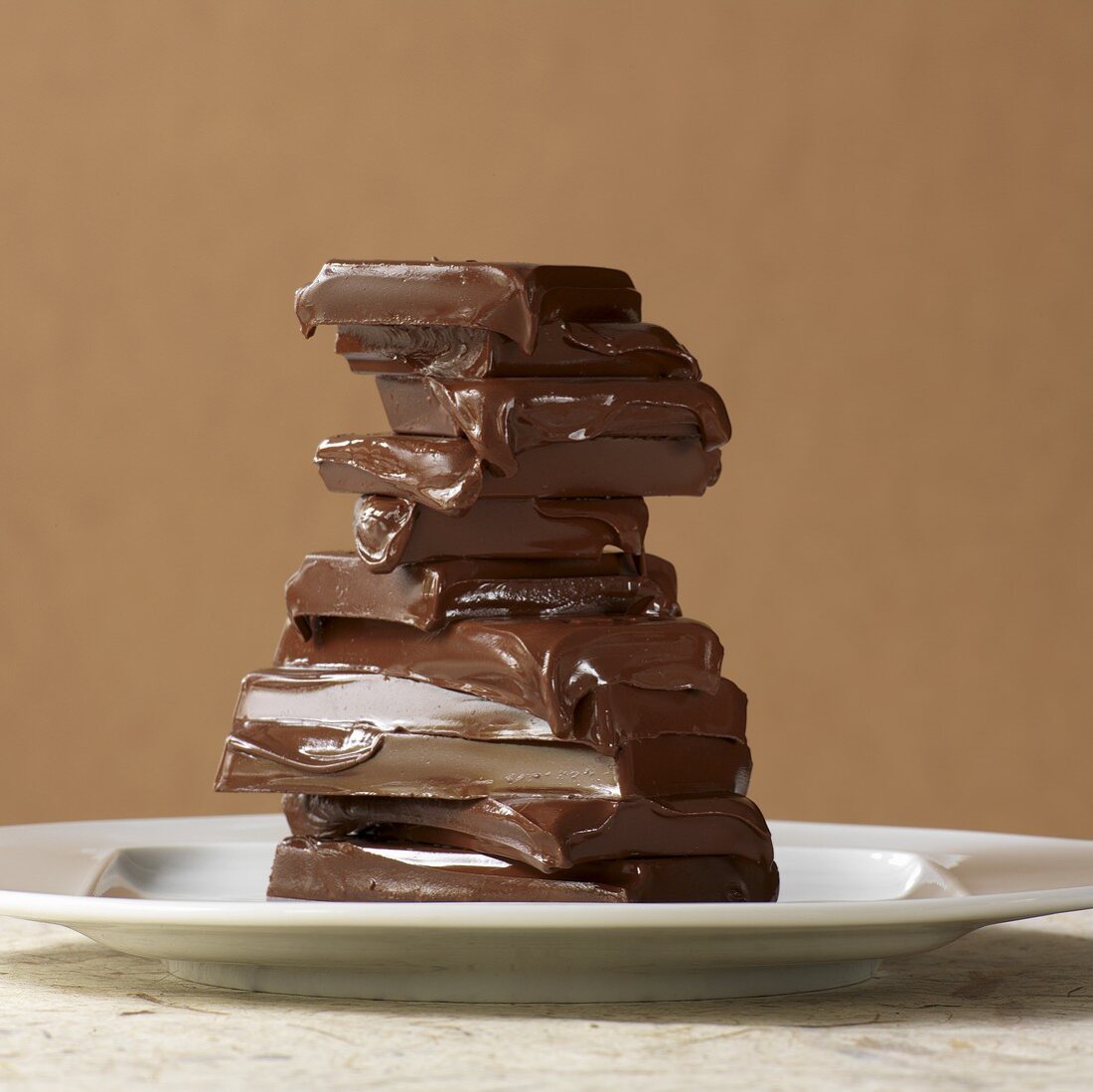 Melted pieces of chocolate stacked in front of a light brown background